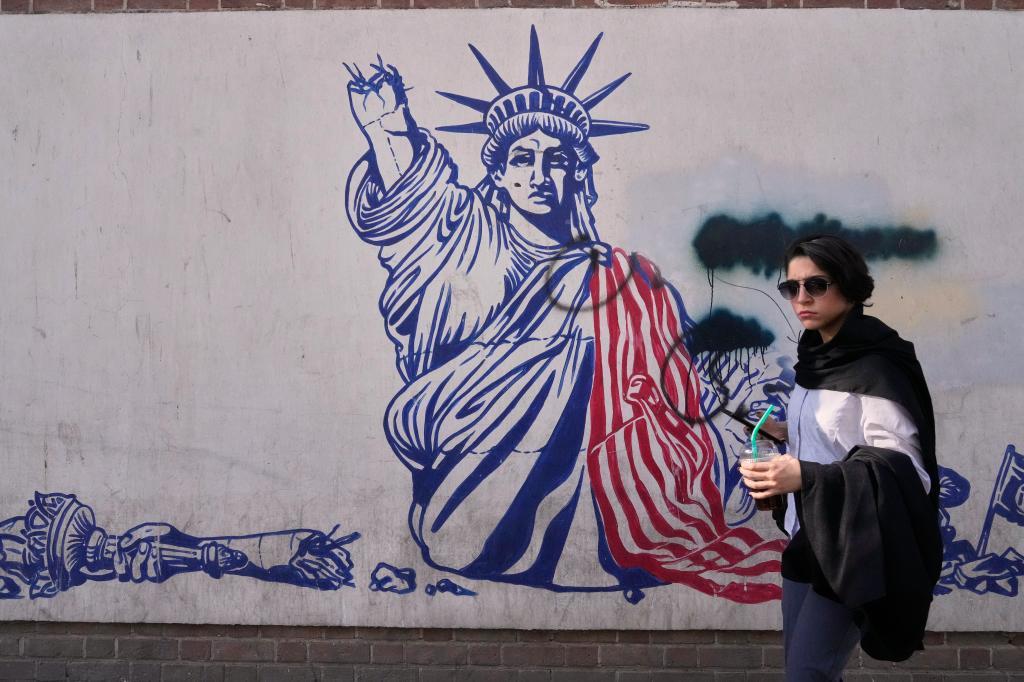 Una mujer pasea junto a un mural anti estadounidense en Teherán.