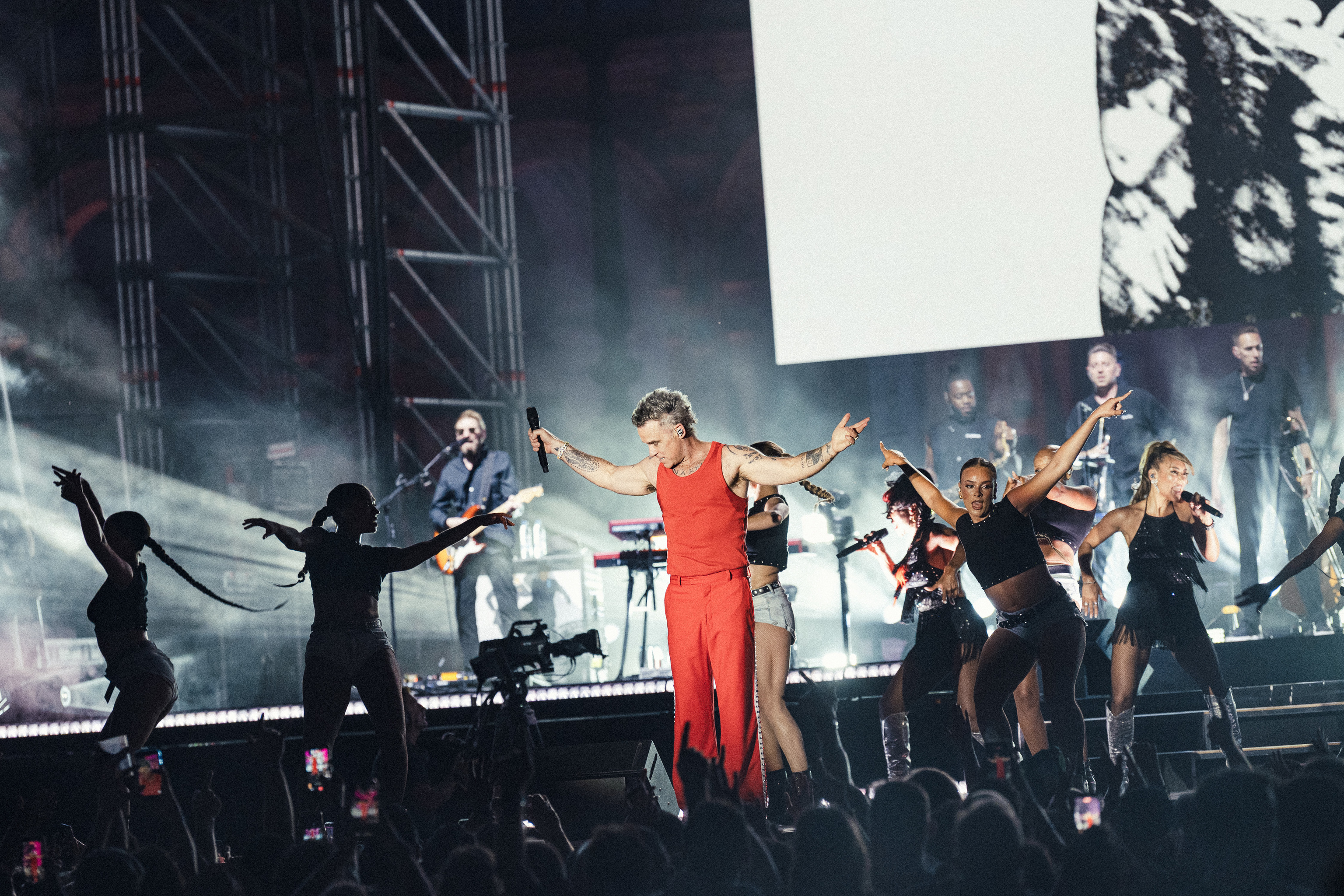 Robbie Williams, en pleno show con músicos y bailarinas.