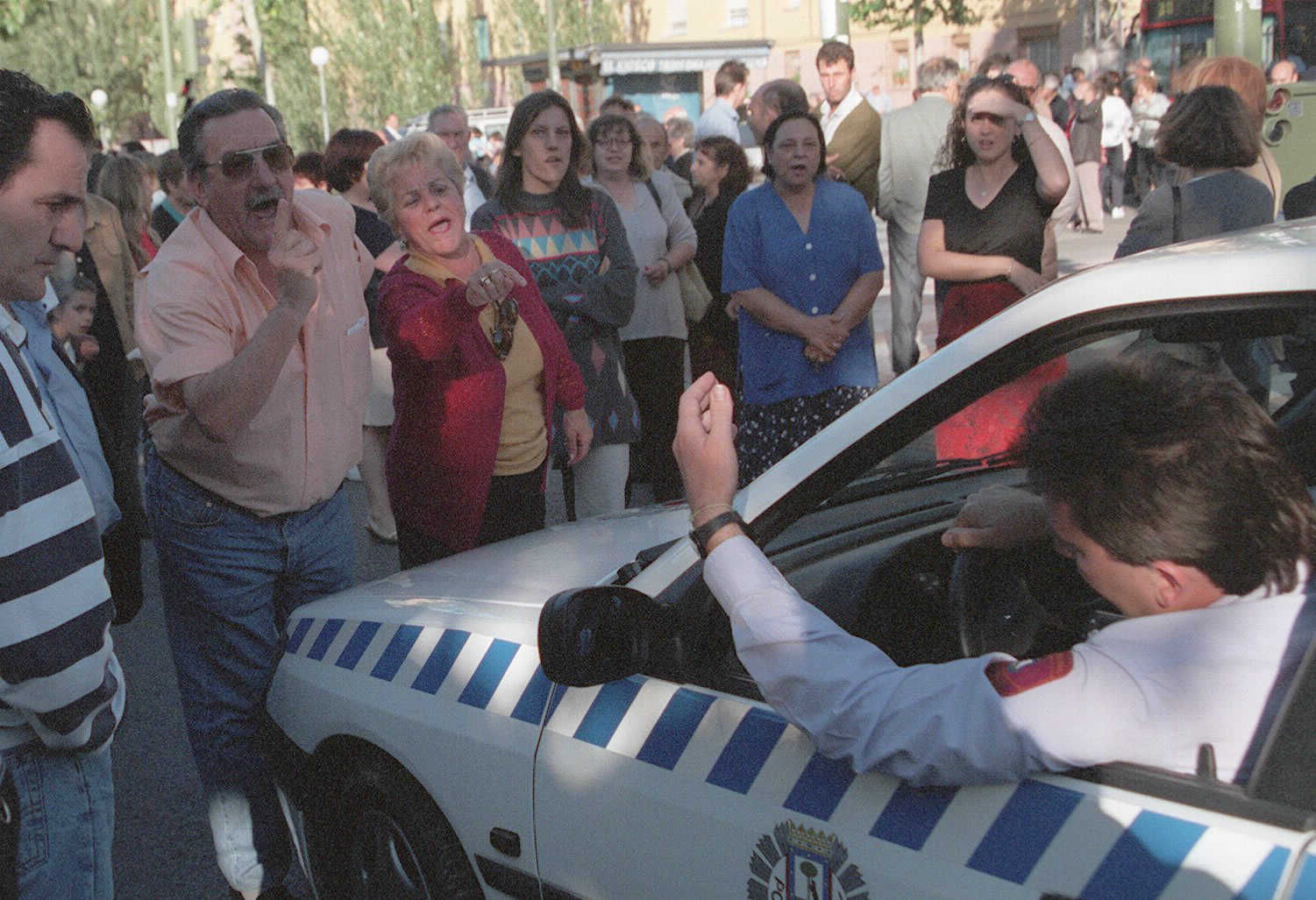 Vecinos de San Blas protestan ante un coche de Policía durante una manifestación reclamando más seguridad.