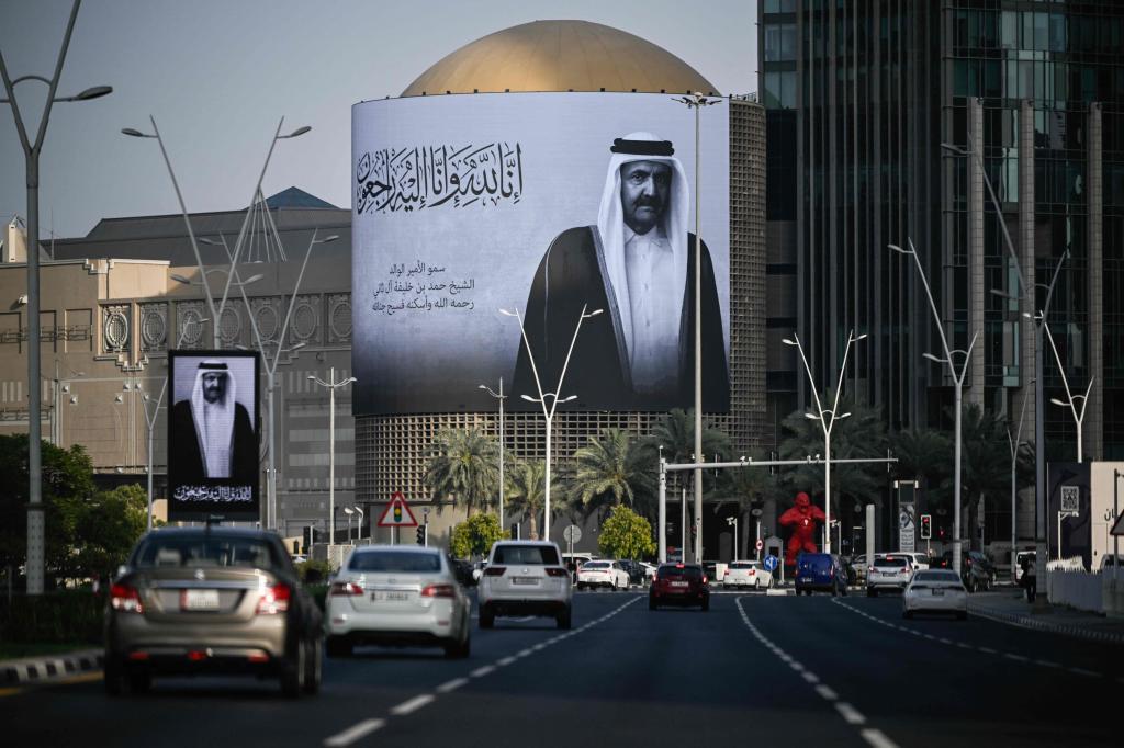 Automovilistas pasan junto a una gigantesca valla con el retrato del ex emir de Qatar, ayer, en Doha.