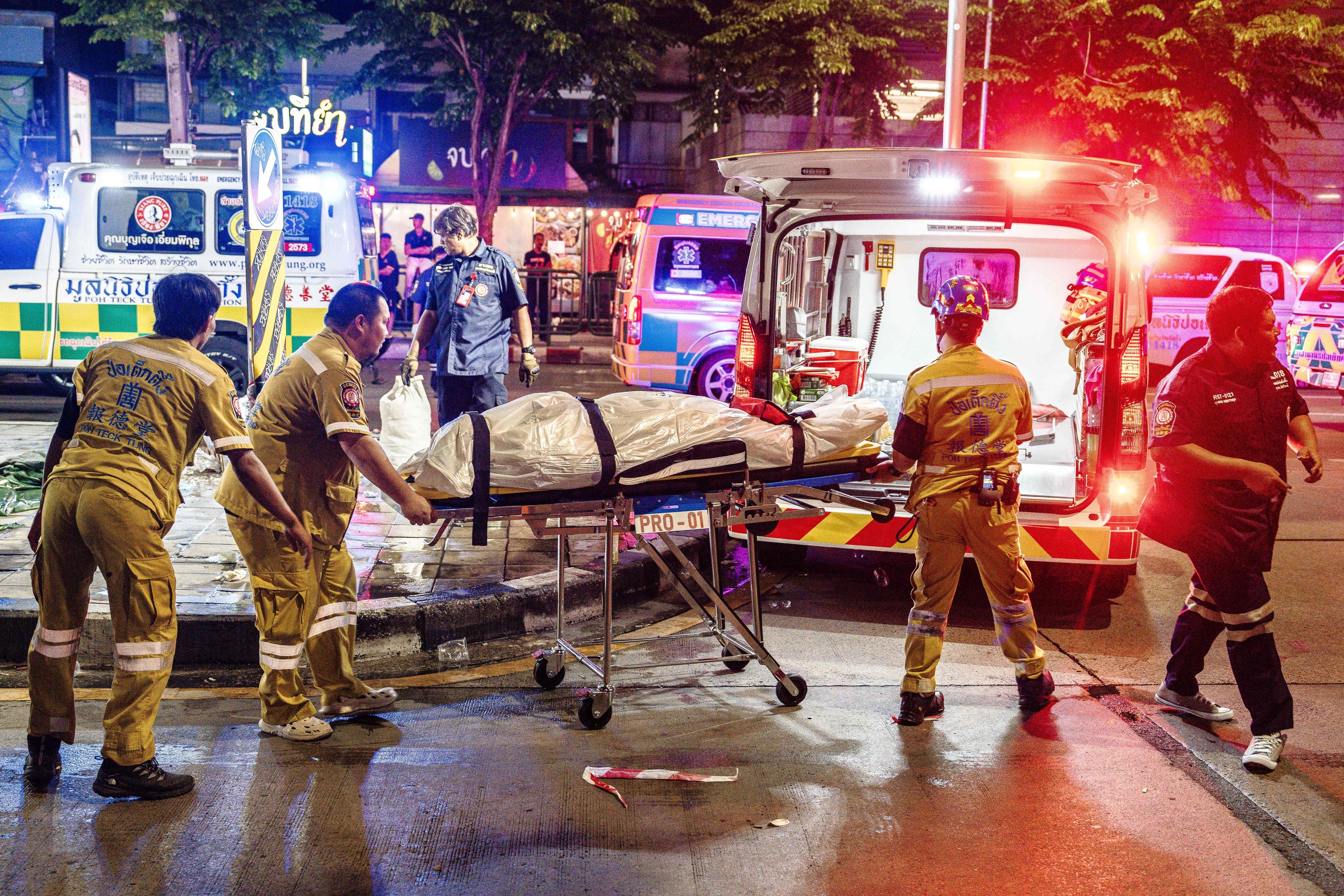 Equipos de emergencia trasladan el cuerpo de una víctima a una ambulancia tras el incendio del pub Na Ladprao en Bangkok.