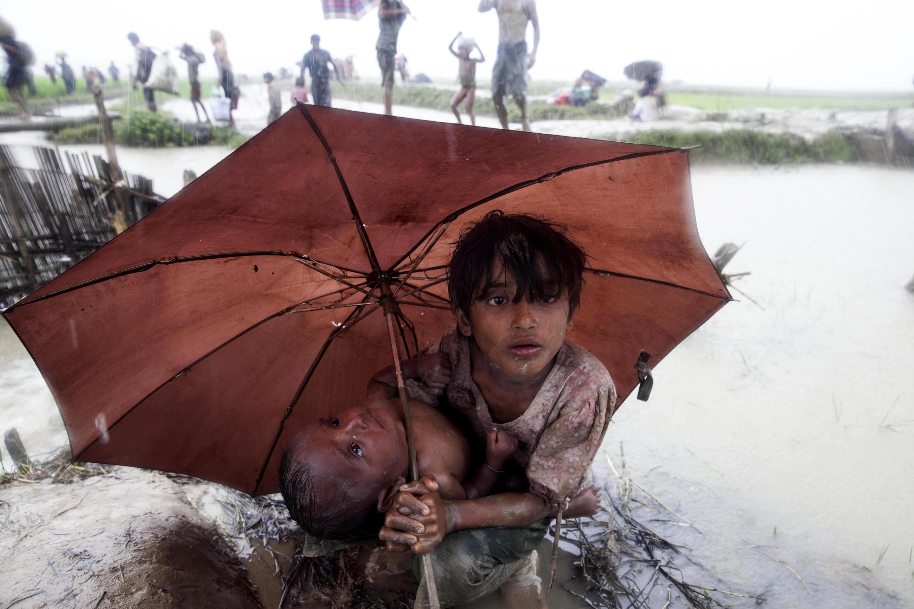 Un niño de la etnia musulmana rohinyá protege a su hermana pequeña de la lluvia en Bangladesh.