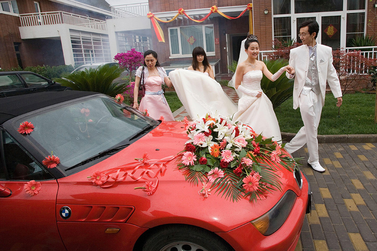 Dos novios chinos caminan hacia su coche para dirigirse a su ceremonia de boda en Pekín.