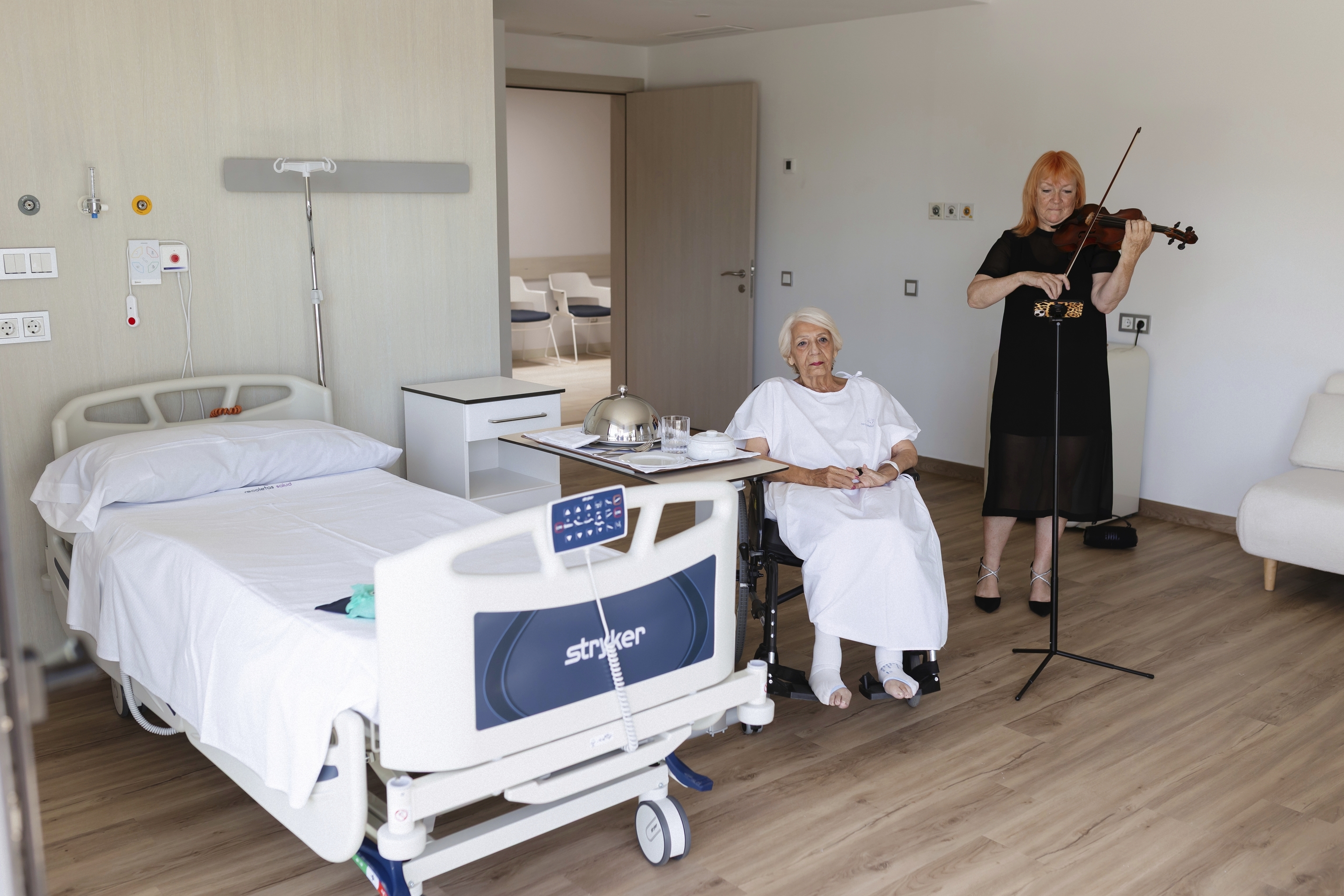 Elena, paciente de 86 años, escucha en su habitación a la violinista Alison Harling.
