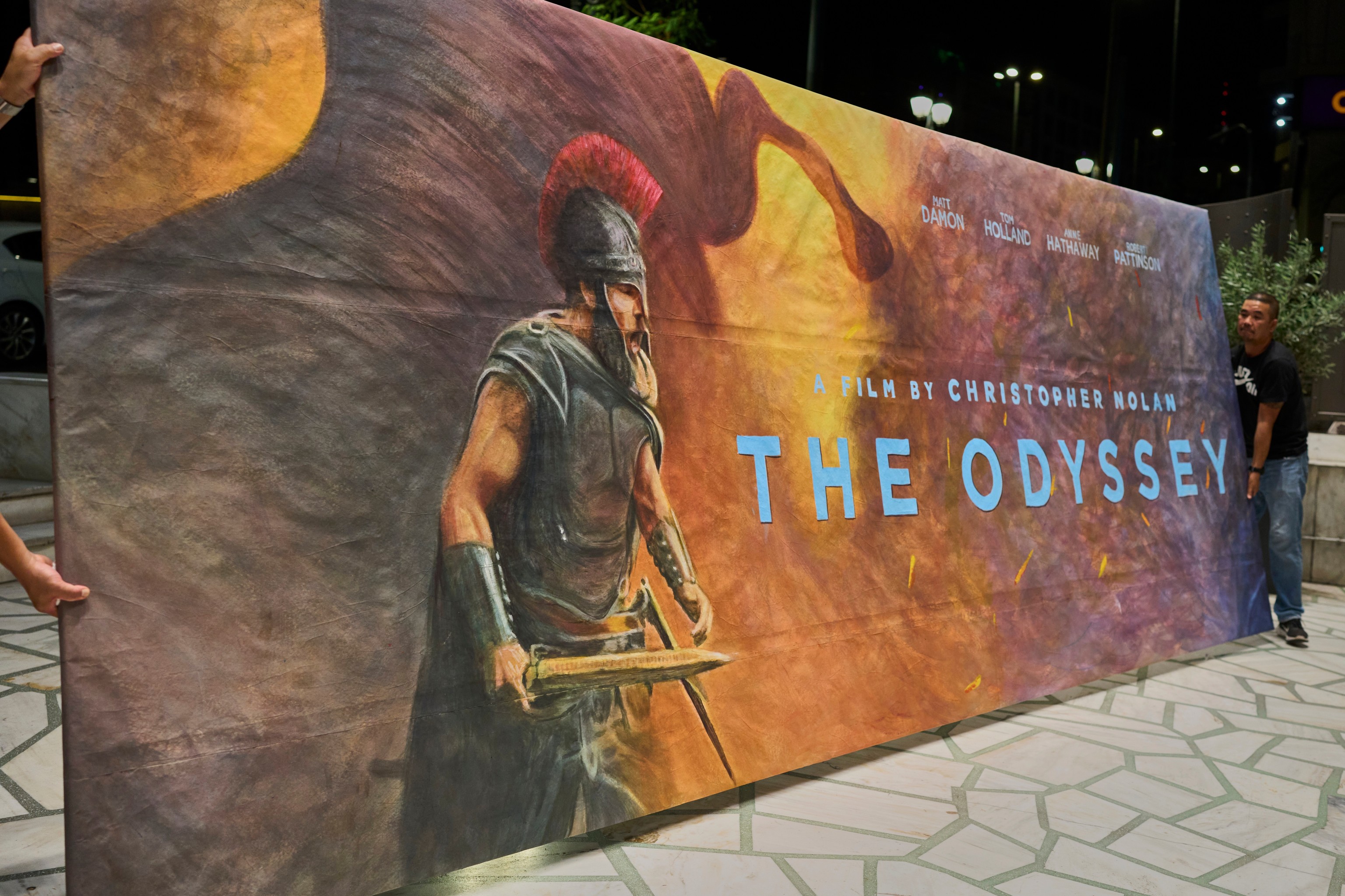Trabajadores instalan un cartel pintado a mano de la película 'The Odyssey', en Atenas.