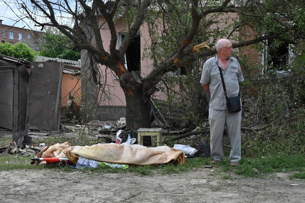 Un hombre permanece junto al cuerpo cubierto de una persona fallecida tras un ataque aéreo en Járkiv este domingo.