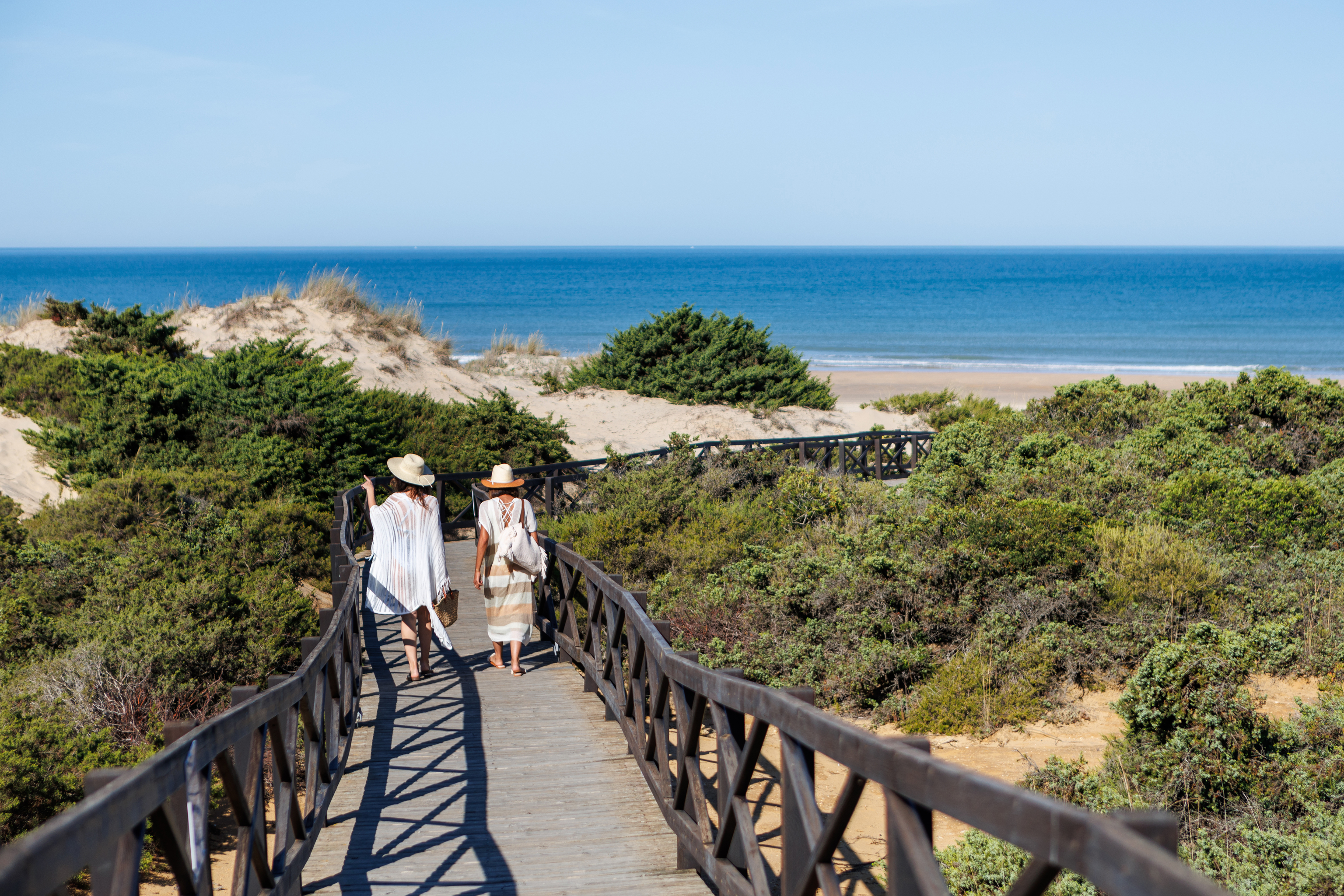 Dos mujeres se encaminan hacia la playa de La Barrosa.