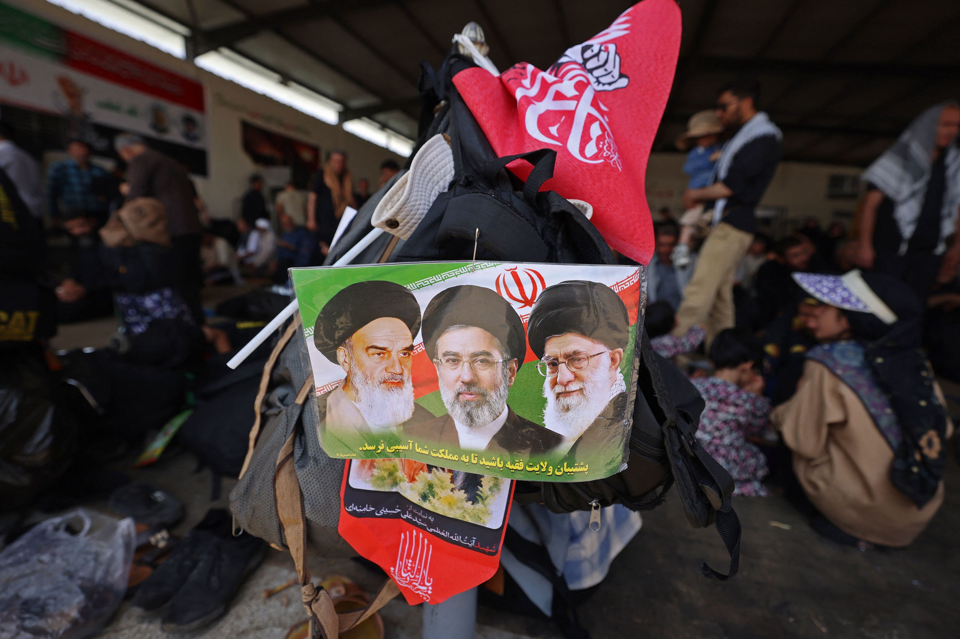 Un hombre porta un cartel en honor a Jomeini, Ali Jamenei y Mojtaba Jamenei, en Teherán.