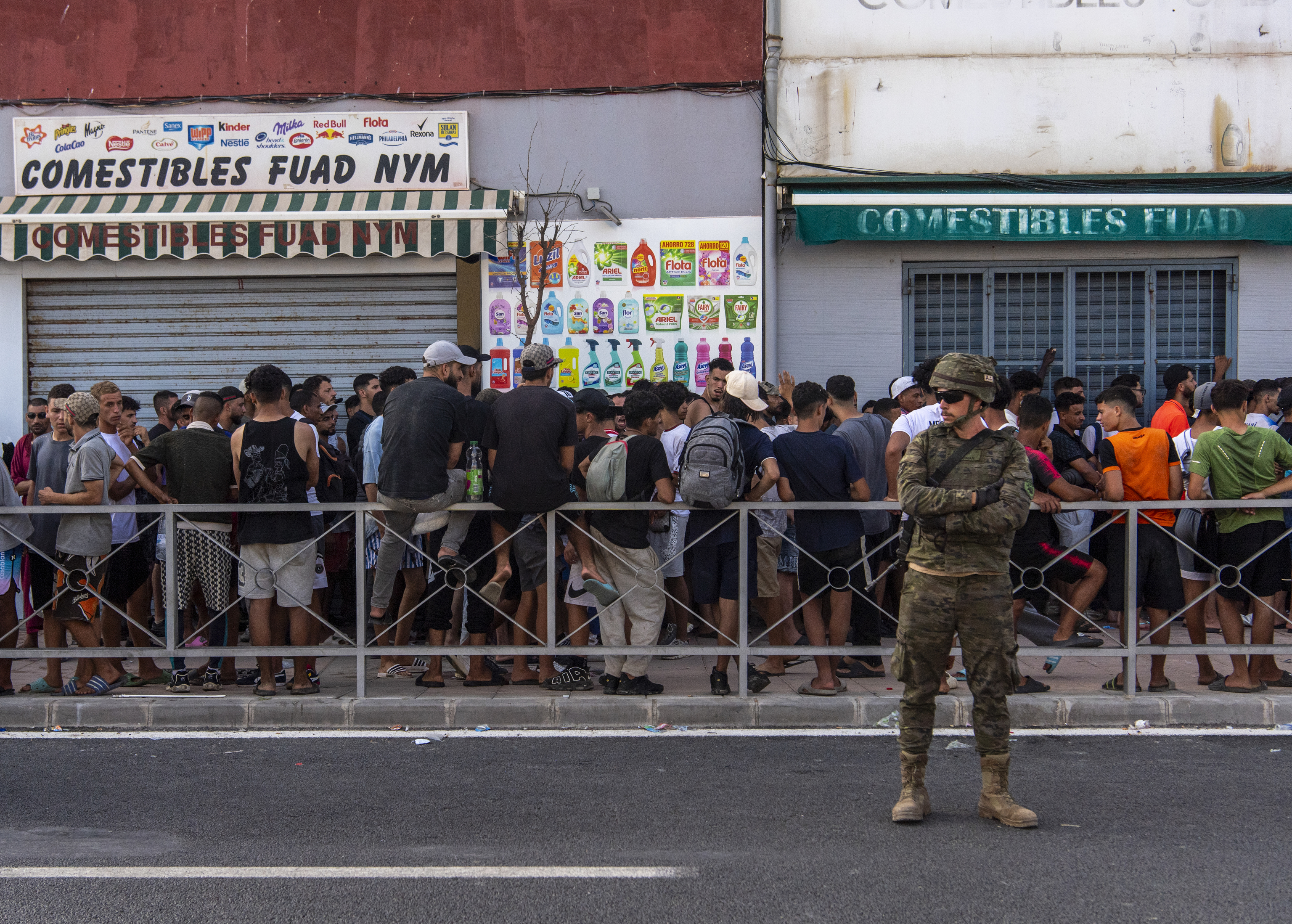 Inmigrantes agrupados en una calle de Ceuta junto a un militar español