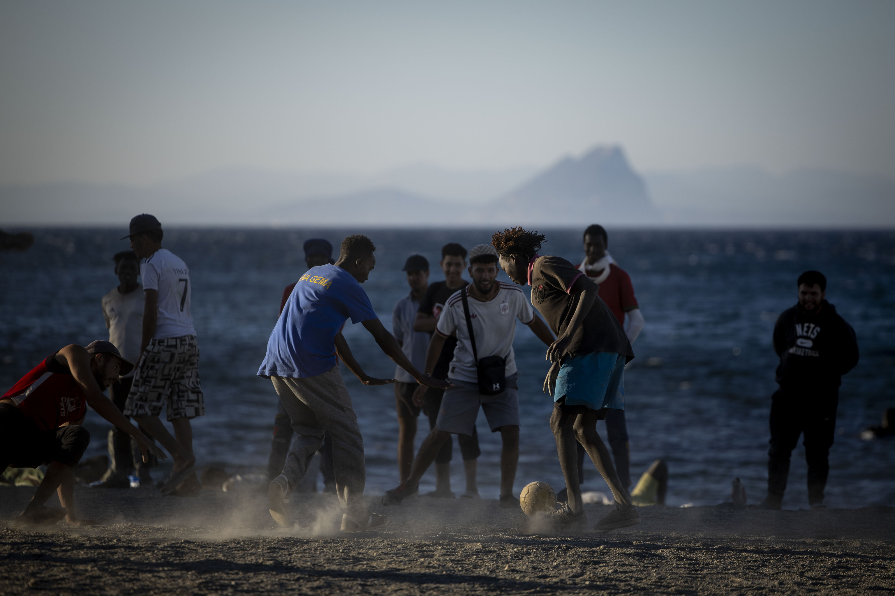 Migrantes subsaharianos en su mayoría juegan mientras esperan un reparto de comida en la playa del Trampolín, ayer en Ceuta