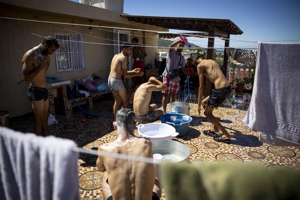 Varios hombres se asean en la azotea de la vivienda.