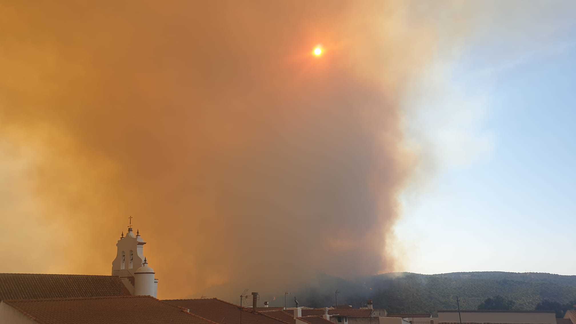 Una nube de humo sobre el perfil del casco urbano de Berrocal (Huelva), esta misma tarde.