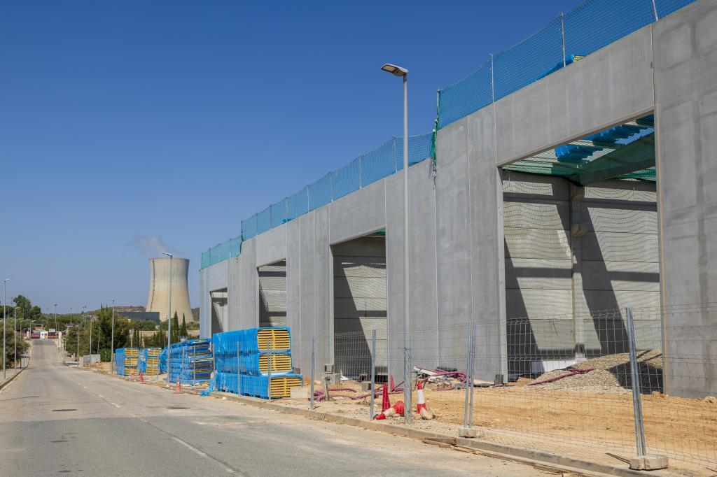 Naves industriales en construcción con la torre de refrigeración de la central nuclear al fondo