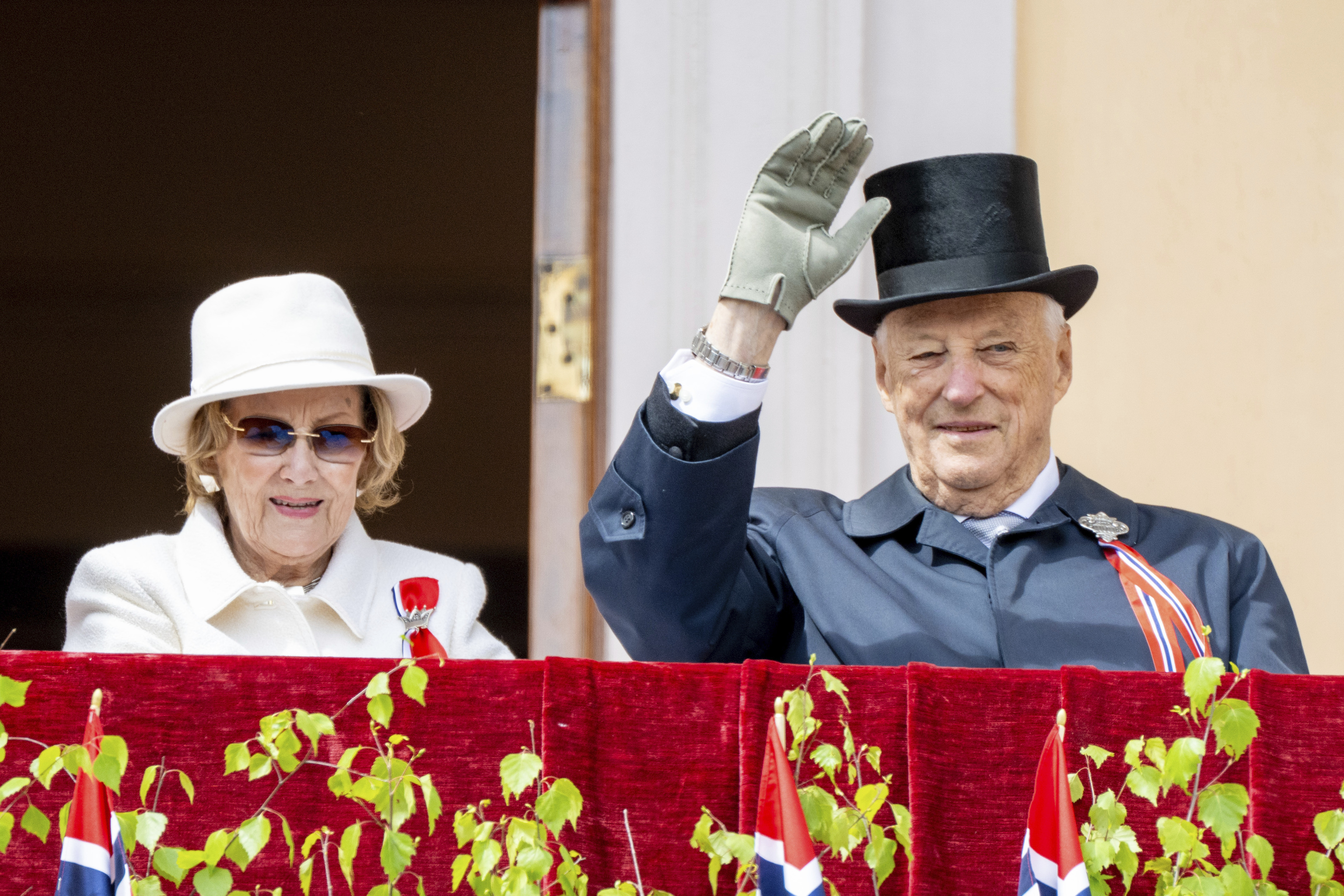 Harald, junto a su mujer, la reina Sonia, saluda desde el Palacio Real.
