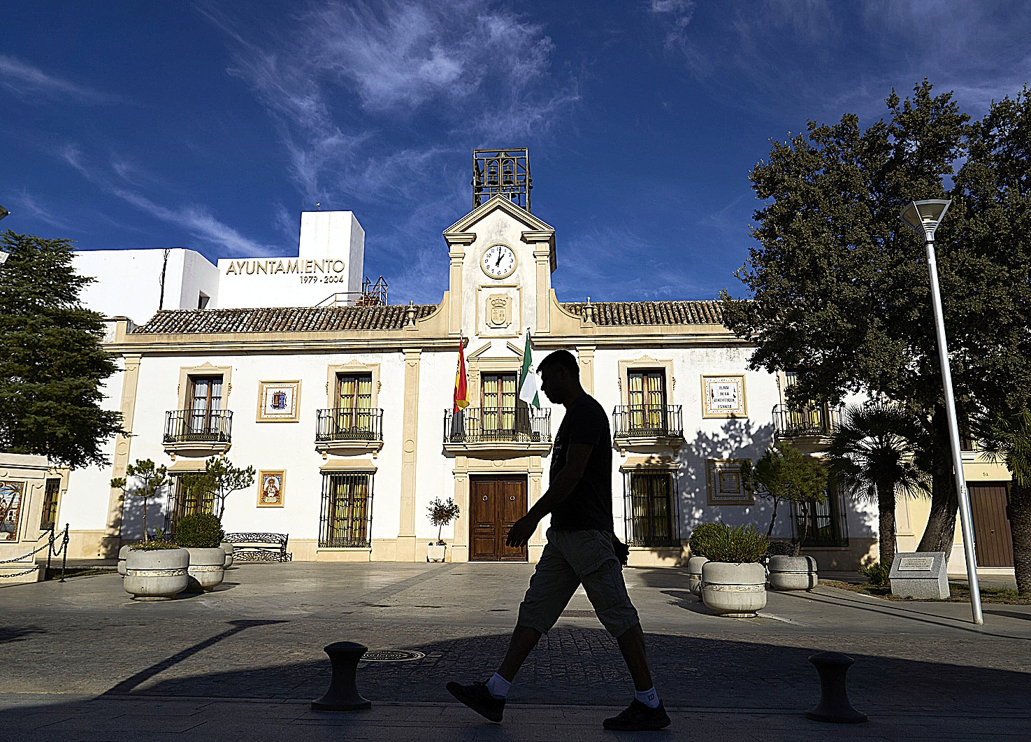 Un hombre pasa frente a la fachada del Ayuntamiento de Burguillos (Sevilla), cuya disoluci�n pide un fondo buitre por una deuda municipal.