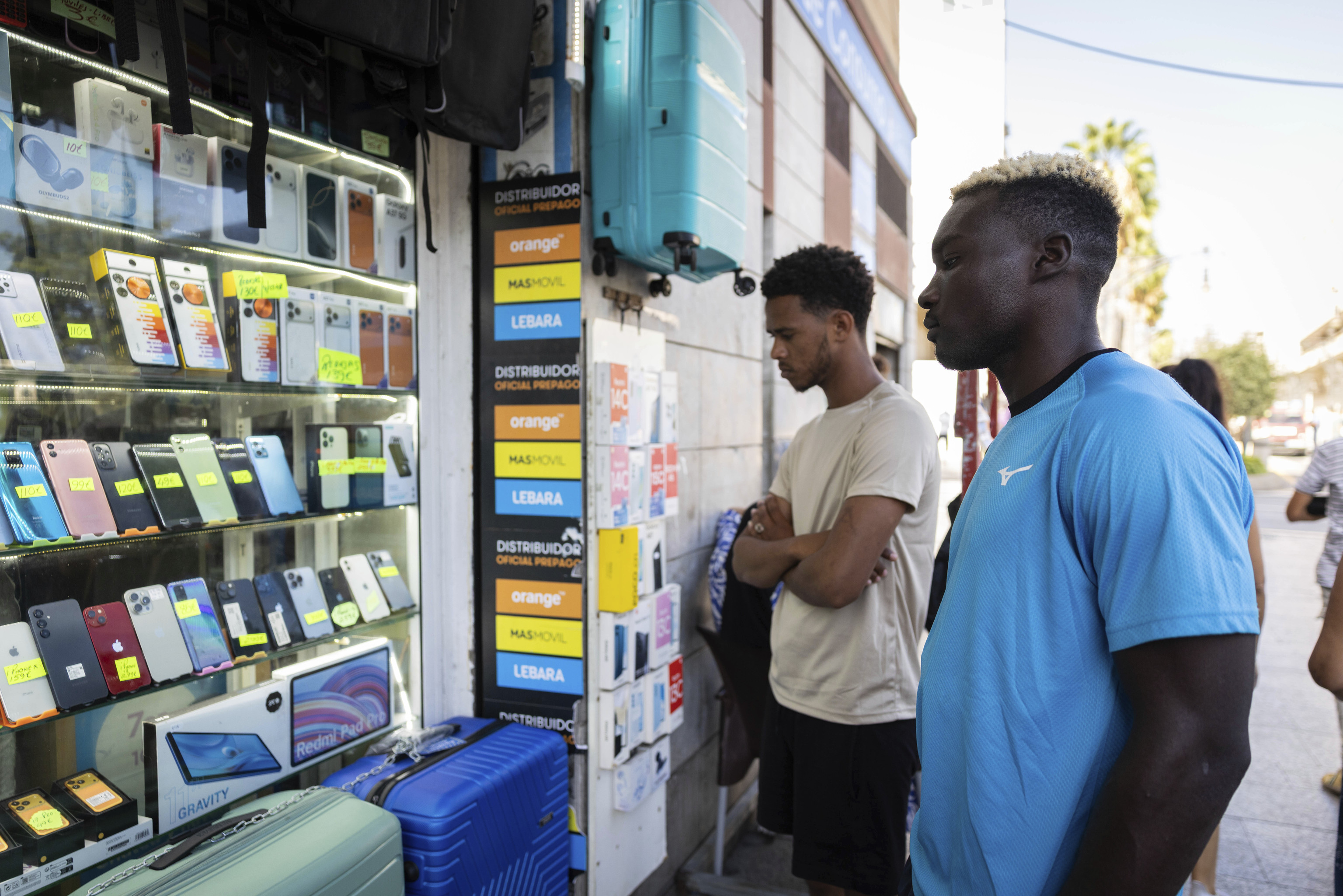 Migrantes observan una tienda de telefonía en la ciudad de Ceuta