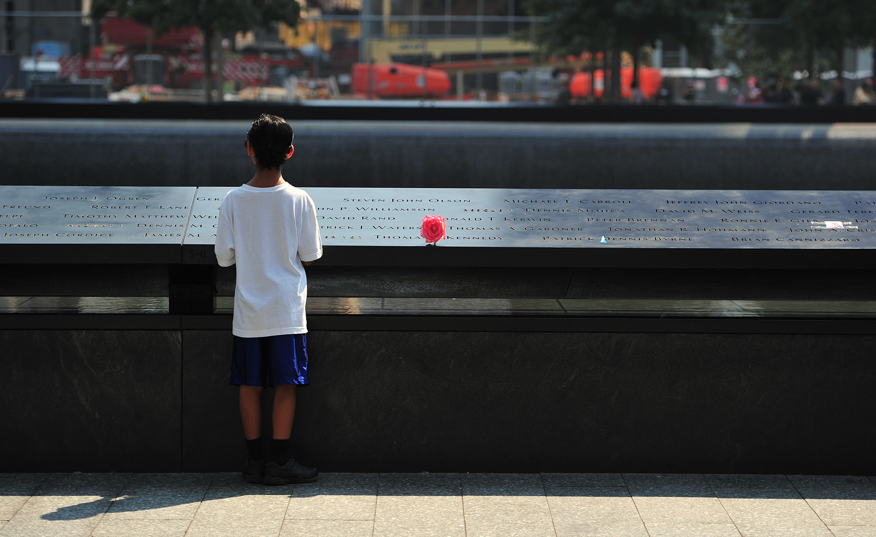 Un niño observa los nombres grabados en el estanque sur del Monumento del 11 de Septiembre.