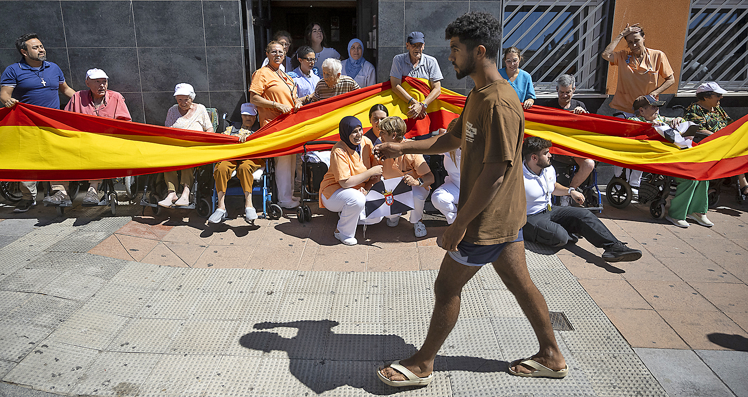 Un inmigrante marroqu� pasa delante de una residencia de ancianos donde se manifiesta un grupo de personas.