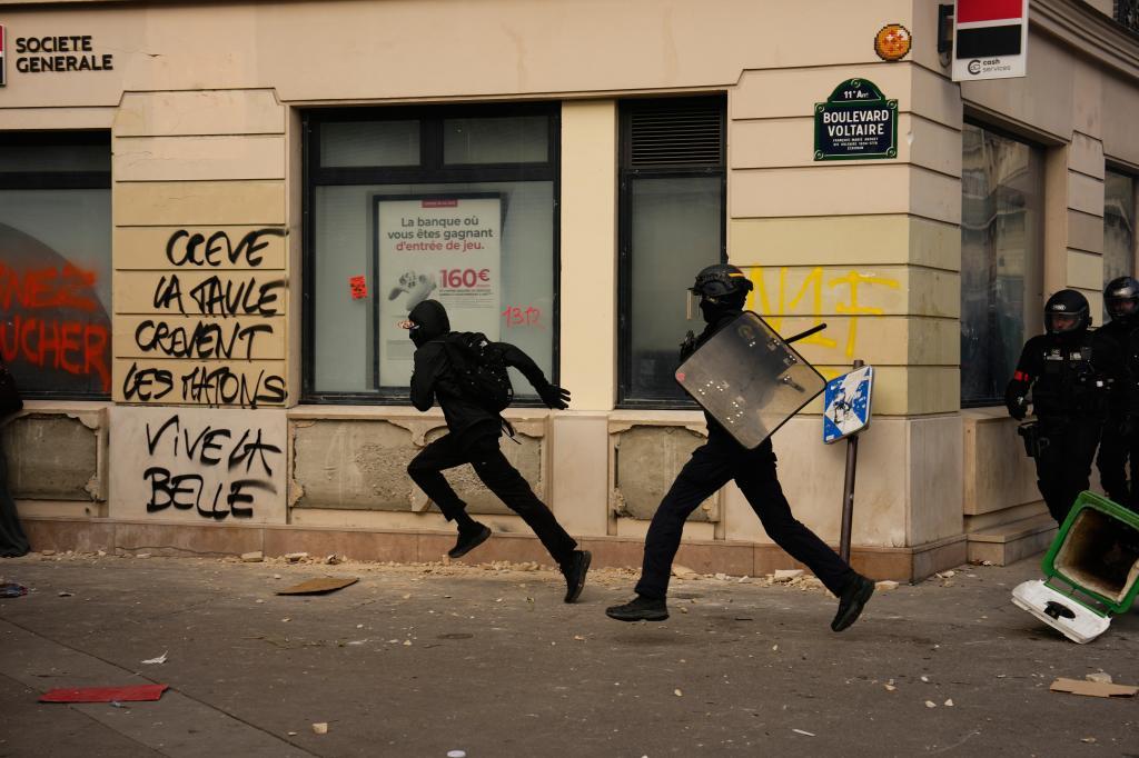 Un agente de policía persigue a un manifestante, ayer, durante los enfrentamientos que se produjeron tras una manifestación, en París.