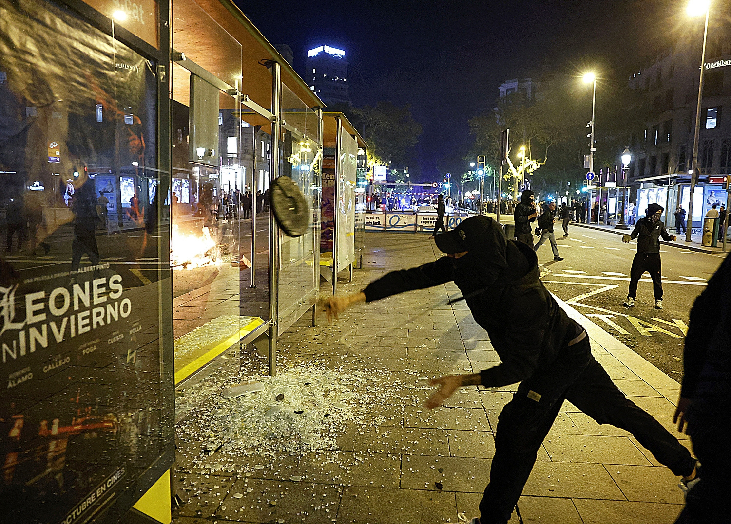 Un embozado lanza un objeto contra el mobiliario urbano de Barcelona.